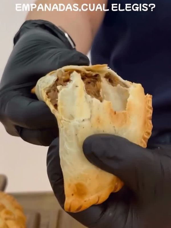 Mano con guante mordiendo una empanada recién horneada